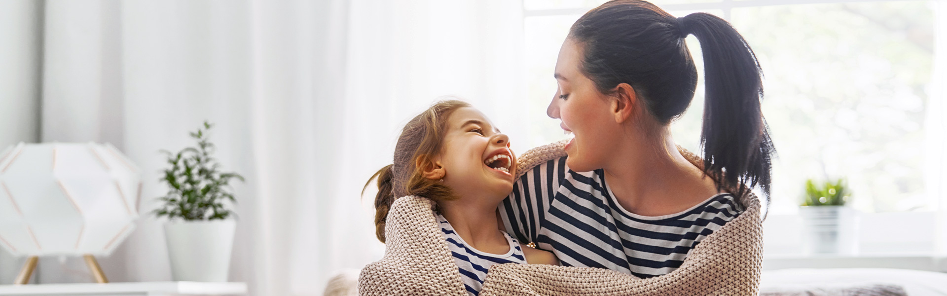 Mom and daughter wrapped in a blanket, playing at home