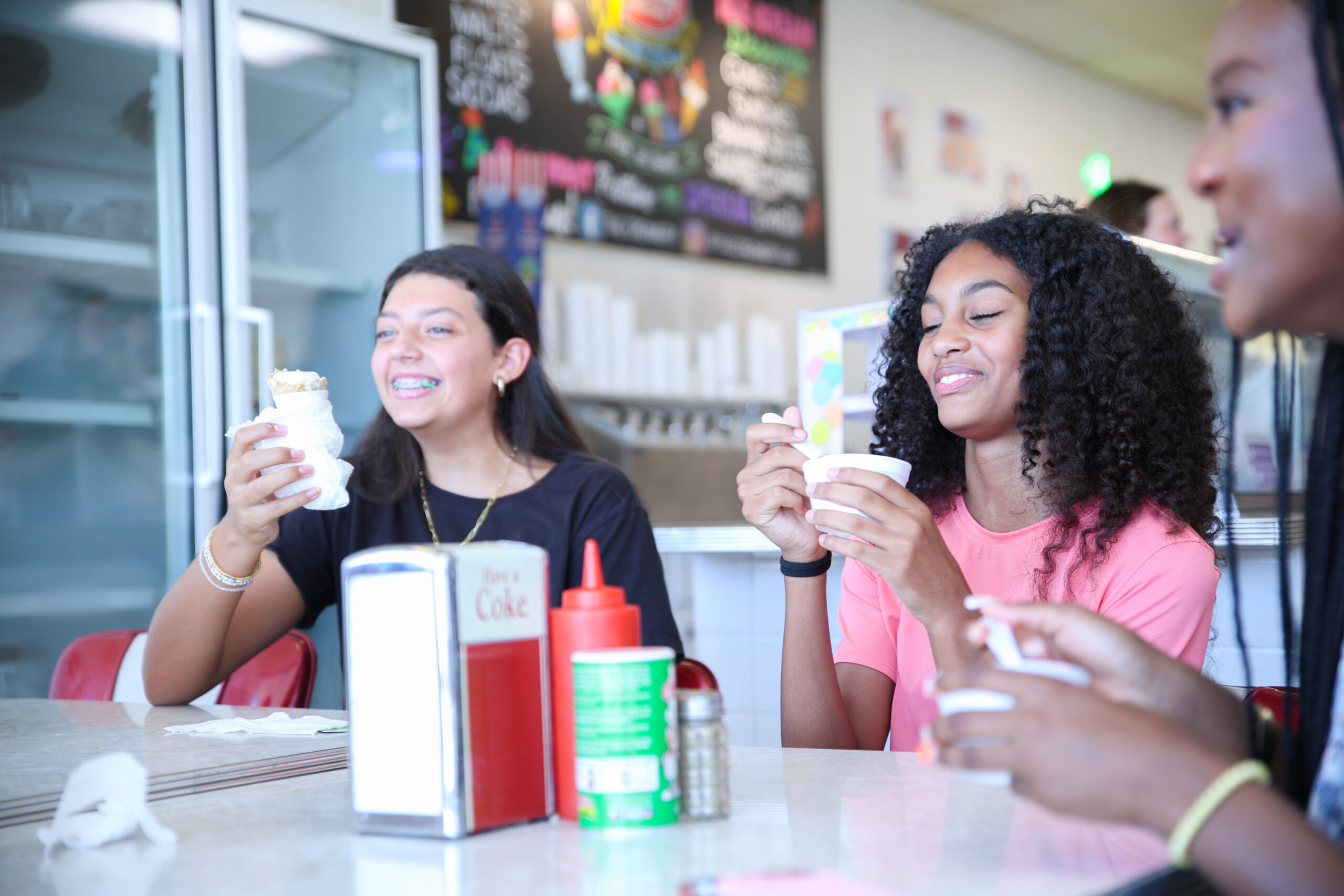 Two girlfriends sitting at a coffeeshop taking selfies