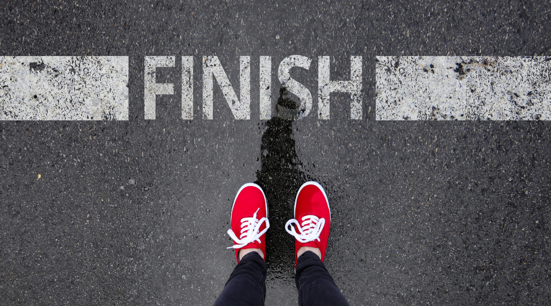 Photo of racing finish line with a woman's shoes about to cross the line